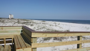 A wooden beach boardwalk with a view of the beach and ocean.