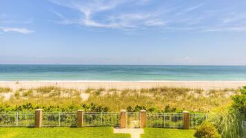 Enjoy stunning ocean views from this beachfront property, surrounded by a well-manicured lawn and an entrance.
