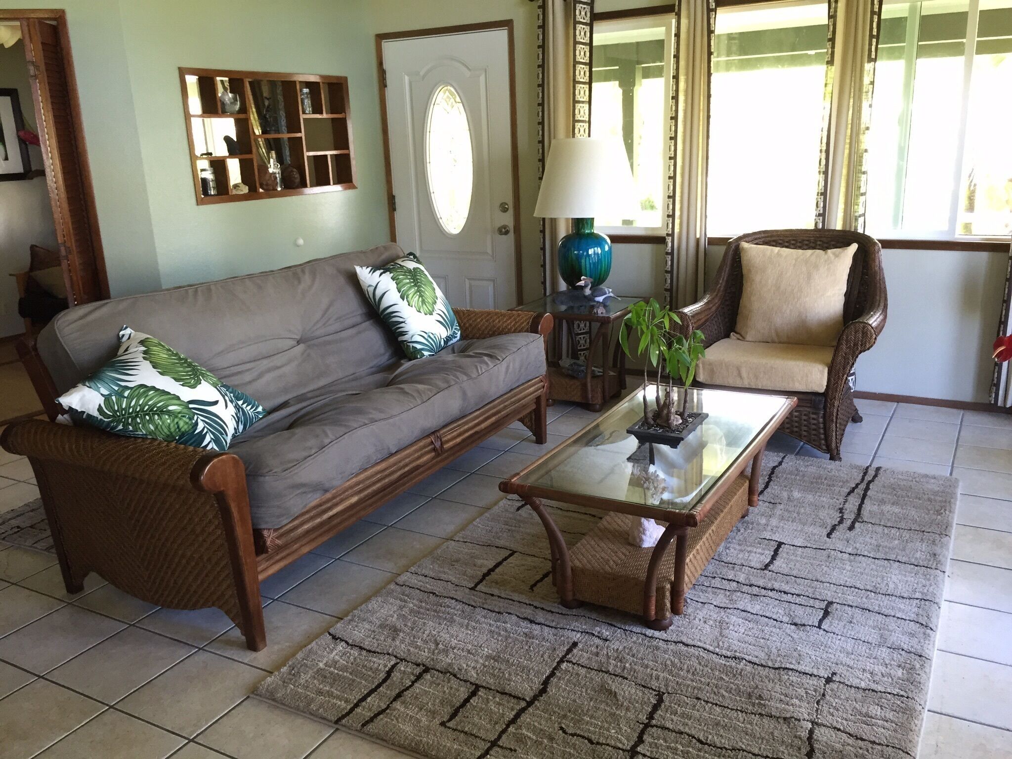 Una sala de estar con sofá, sillón, mesa de centro y un espejo decorativo.