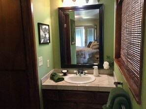 Une salle de bain avec un grand miroir, un lavabo et une serviette verte.