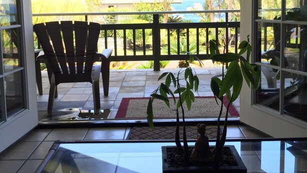 Ein Zimmer mit Glastür und Zugang zu einem Balkon mit einem Stuhl und einer kleinen Pflanze.