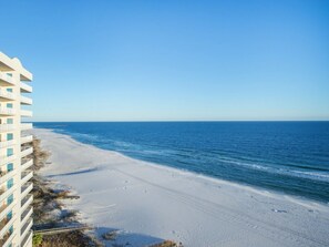 A beachfront hotel with a clear view of the ocean, sandy beach, and a clear sky.