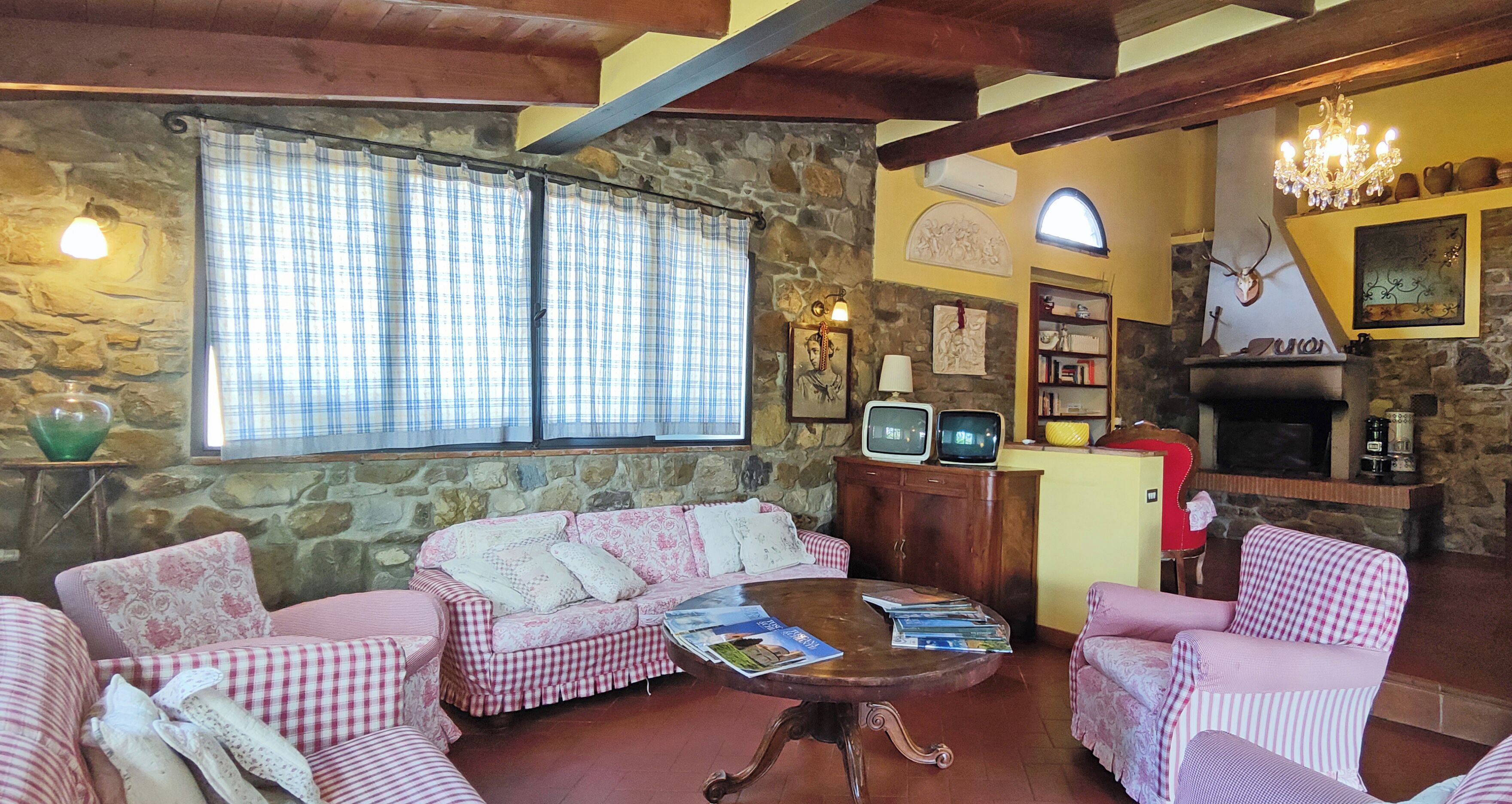 A cozy living room with a stone wall, checkered furniture, a fireplace, and a television set.