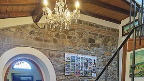 Una escalera conduce a un segundo piso con un muro de piedra y un candelabro.
