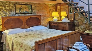 Un dormitorio con cama de madera, mesita de noche, dos lámparas, un espejo y una escalera que lleva a un nivel superior.