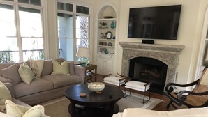 A living room with a fireplace, a sofa, a coffee table, and a TV mounted on the wall. - Gorgeous Home 5 minute walk to beach (Kiawah Island)