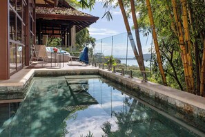 A pool with a view of a mountain and bamboo trees.