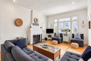 A modern living room with a fireplace, grey sofas, a coffee table, and a television.