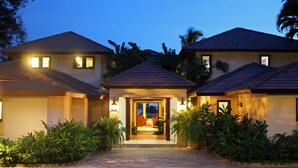 A two-story house with a central entrance, surrounded by lush greenery. - Oceanfront, On Golf Course, Next to Beach, heated pool & hot tub, fully staffed (La Romana, CASA DE CAMPO)