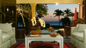 A living room with a view of the ocean, featuring a white sofa, a coffee table, and a red patterned rug. - Oceanfront, On Golf Course, Next to Beach, heated pool & hot tub, fully staffed (La Romana, CASA DE CAMPO)