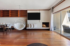 Ein modernes Wohnzimmer mit Hängekorbschaukel, Kamin, Essbereich und großem Fenster.