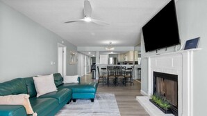 Un salon moderne avec un canapé de couleur turquoise, une cheminée et un téléviseur fixé au-dessus.