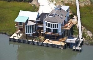 A waterfront property with a large house featuring multiple decks and a dock extending into the water. - Eureka! on Deep Hole Creek - Waterfront!  Sleeps 16  (Chincoteague)