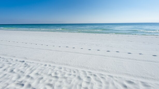 Une plage de sable blanc bordée d’une eau d’un bleu cristallin.