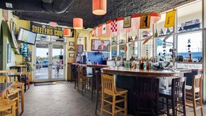 Un bar avec des chaises en bois et un comptoir où sont exposées différentes bouteilles.
