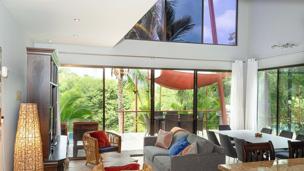 A spacious living area with a large window, a dining table, and comfortable seating. - Private Rainforest Retreat with Infinity Pool & Concierge (Quepos)