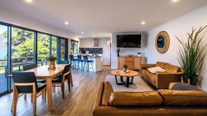 A modern living room with a sofa, coffee table, and dining area. - Harbour Master - Freycinet Holiday Houses (Coles Bay)