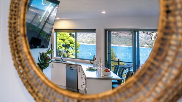 A modern kitchen with a large window overlooking a scenic coastal view. - Harbour Master - Freycinet Holiday Houses (Coles Bay)
