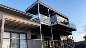 Two-story building with a spacious balcony and glass railing, featuring a staircase and large windows.