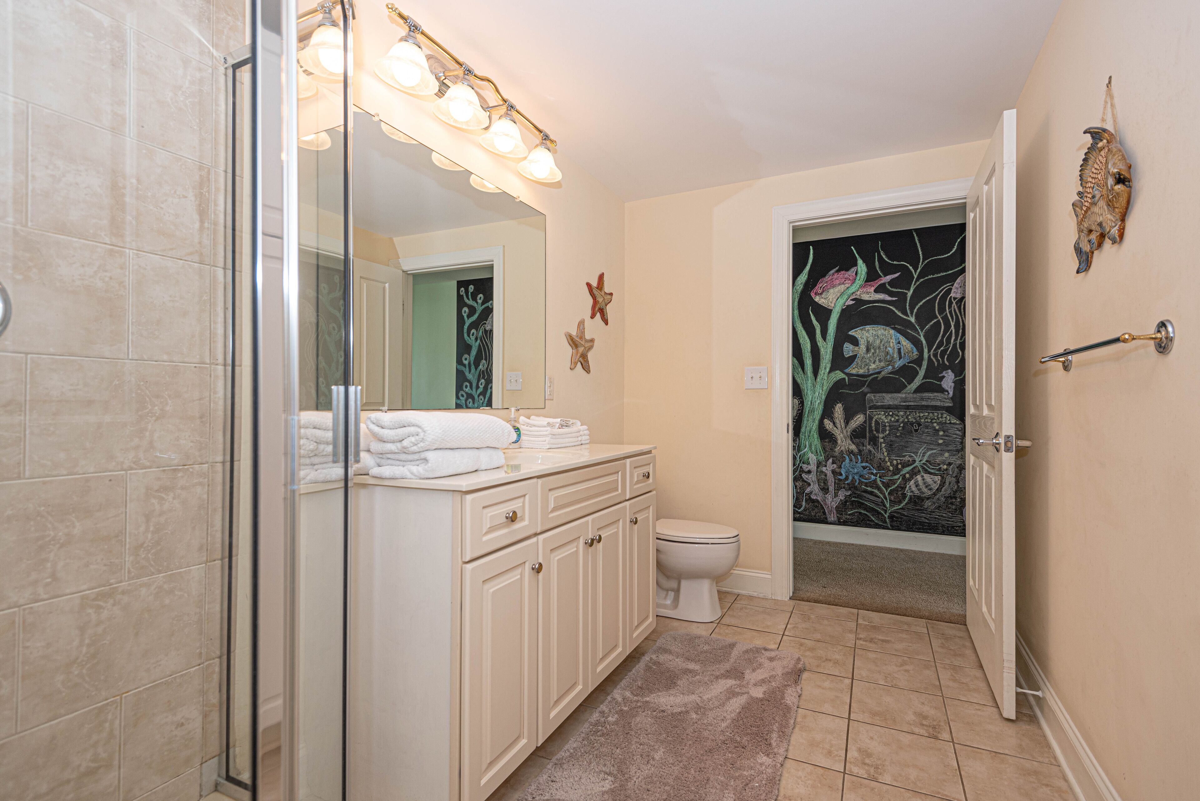 A bathroom with a glass shower enclosure, a white sink with a mirror, and a toilet.