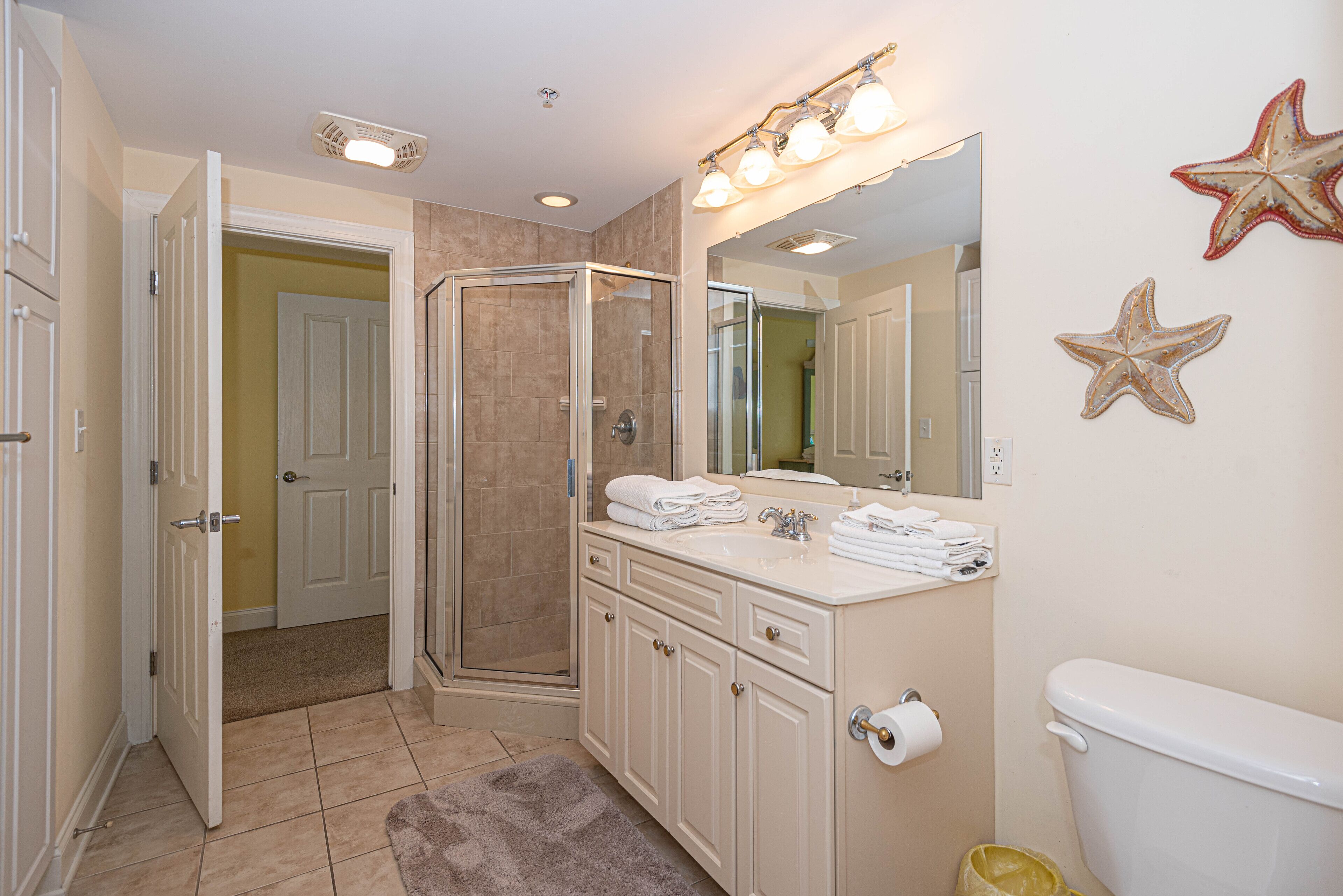 A bathroom with a glass-enclosed shower, a vanity with a mirror, and a toilet.