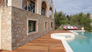 A stone building with a pool and wooden deck. - Breathtaking mediterranean view, large private infinite Pool & Jacuzzi ! (Theologos)