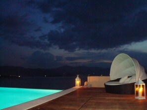 A poolside area with a lounge chair and two lanterns. - Breathtaking mediterranean view, large private infinite Pool & Jacuzzi ! (Theologos)