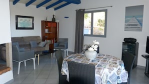 A living room with a sofa, a dining table with chairs, a bookshelf, and a TV. - Detached house with beautiful sea view, enclosed garden and garage  (Zonza)