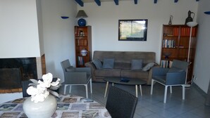 A living room with a sofa, two armchairs, a coffee table, a fireplace, a bookshelf, and a window. - Detached house with beautiful sea view, enclosed garden and garage  (Zonza)