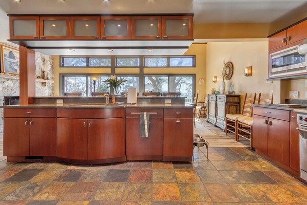 A spacious kitchen with a large island, wooden cabinets, and a stone backsplash. - Spectacular Views, Close to everything Rehoboth + Pet Friendly! (Rehoboth Beach)