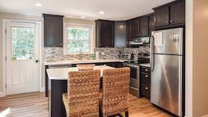 A kitchen with dark cabinets, a stainless steel refrigerator, and a tiled backsplash. - Amazing Backyard, Spacious, Dog Friendly! (Dennis)
