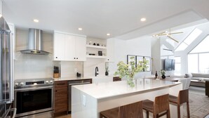 A modern kitchen with a central island, stainless steel appliances, and wooden bar stools. - LUXURY- 2BA/BA True Ski-in/Ski-out, HotTub&Pool (Whistler)