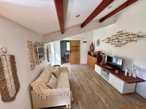 A living room with a sofa, TV stand, and decorative wall art.
