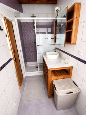 Ein modernes Badezimmer mit einer gläsernen Duschkabine, einem hölzernen Waschtisch, einem Marmorbecken und einem Einbauschrank.