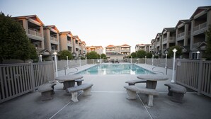Una piscina con bancos, rodeada de edificios de apartamentos con balcones.