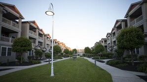 Una hilera de edificios de apartamentos modernos con balcones, un camino central y una farola.
