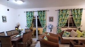 A living room with wicker furniture, a dining table, and a fan. - Superb apartment-300m from beach (Rate incl. free WiFi, maid service, parking..) (Flic en Flac)