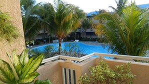 A pool area with palm trees and a view of a building in the background. - Superb apartment-300m from beach (Rate incl. free WiFi, maid service, parking..) (Flic en Flac)