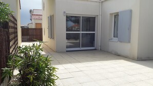 A clean, tiled patio area with a sliding glass door leading to a covered outdoor space. - Apartment in a small quiet residence near the sea (Château-D'olonne)