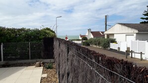 A coastal residential area with a paved walkway, a metal fence, and a view of the sea. - Apartment in a small quiet residence near the sea (Château-D'olonne)