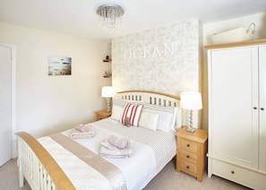 A bedroom with a bed, bedside tables, a wardrobe, and a wall with the word "OCEAN" on it.
