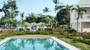 A swimming pool surrounded by greenery and a building with a modern design. - Beachfront Apartment facing Playa Popy (Las Terrenas)