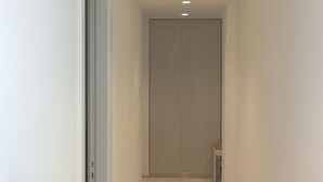 Un couloir étroit avec un plancher en bois, des murs blancs et une porte au fond.