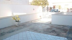 Un patio carrelé avec une plante en pot et un mur blanc.