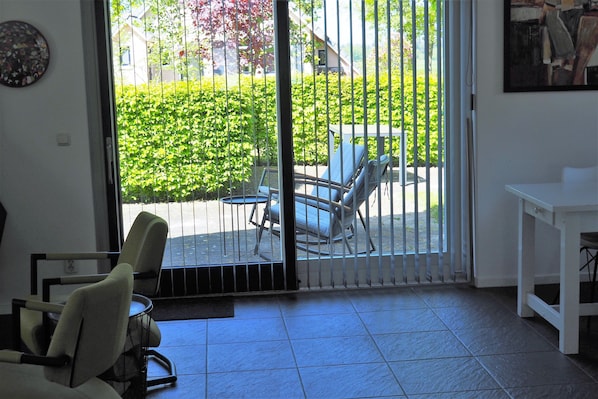 A room with a sliding glass door leading to an outdoor seating area with chairs and a table.