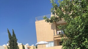 Un quartier résidentiel avec des bâtiments modernes, un chemin en béton et une végétation luxuriante.