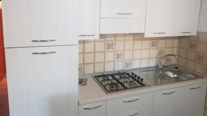 A kitchen with white cabinets, a gas stove, and a sink. - Gallura House Sardinia (trinita d agultu e vignola)