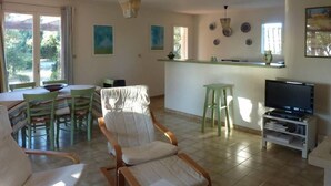 Een woonkamer met een eethoek, keuken en televisie.