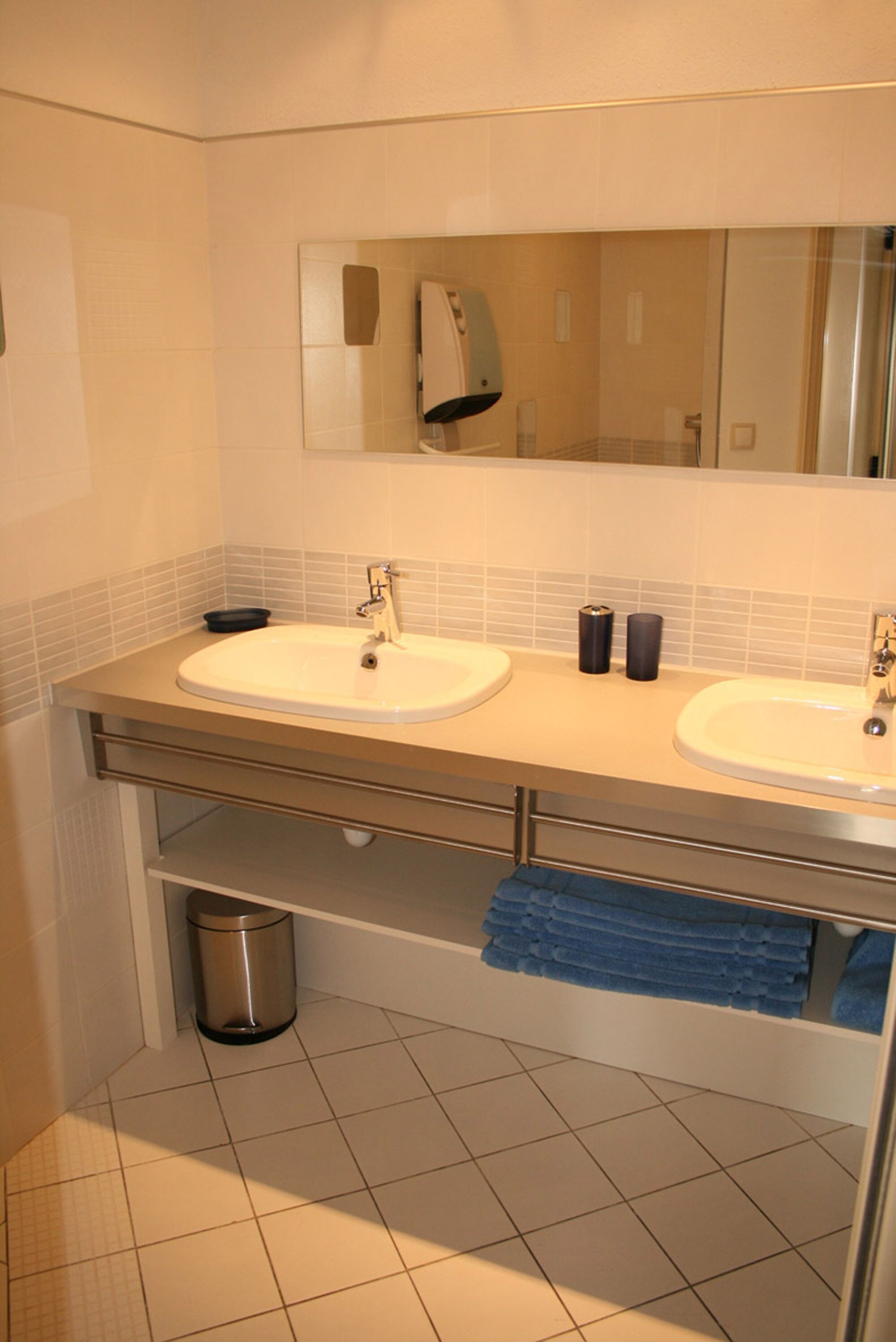 Un baño con dos lavamanos, un espejo y un perchero para toallas.