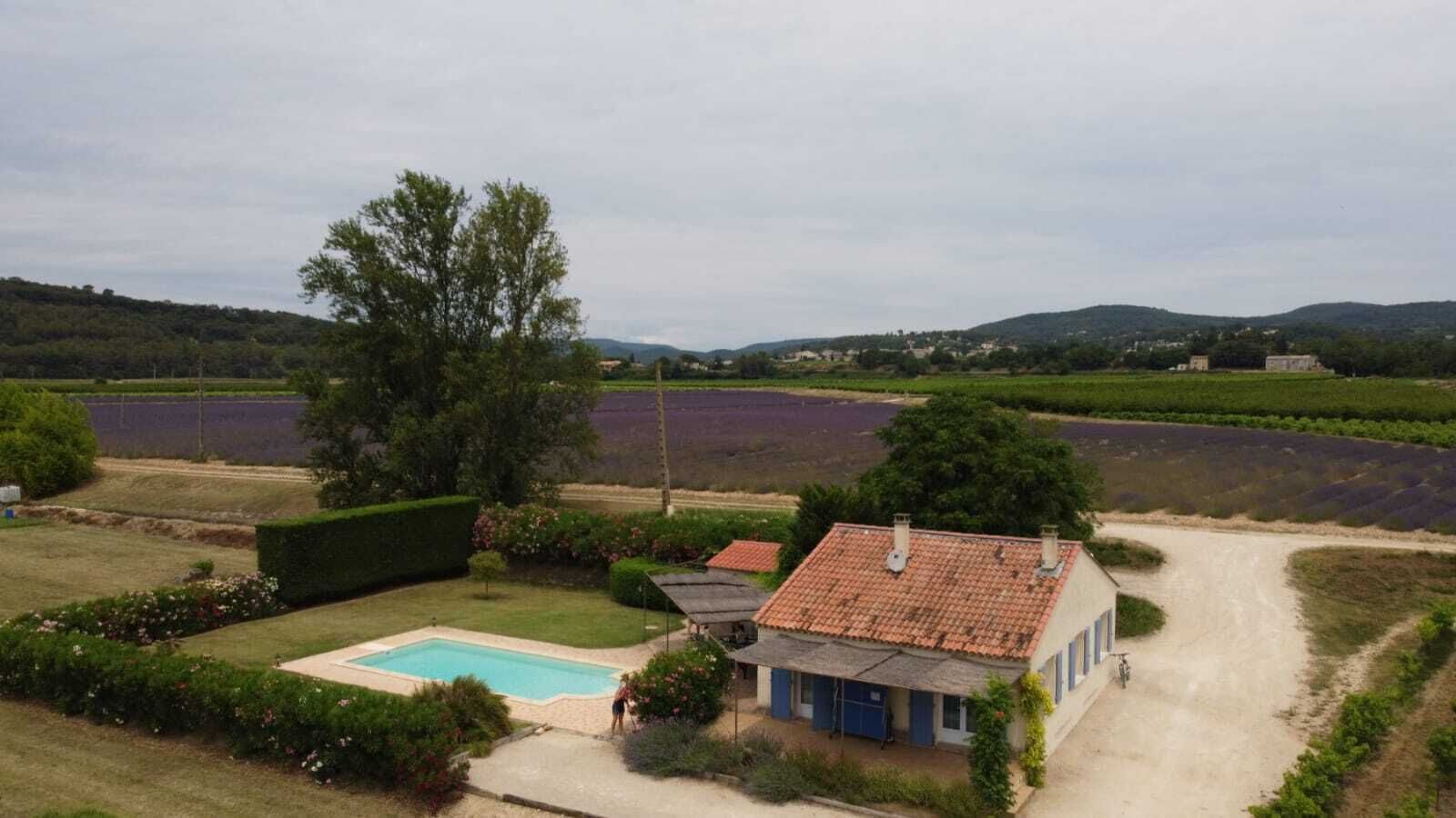 A house with a swimming pool, surrounded by a garden and fields.